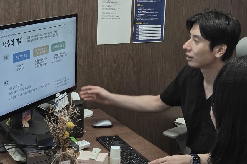 모니터의 검사 결과를 가리키며 설명하는 모습 — 호랑이부부한의원 진료실